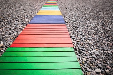 Colorful wooden walkway on stony beach, closeup