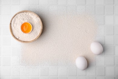 Flour and raw eggs on white tiled table, flat lay