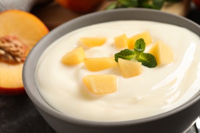 Photo of Delicious yogurt with fresh peach and mint in bowl, closeup