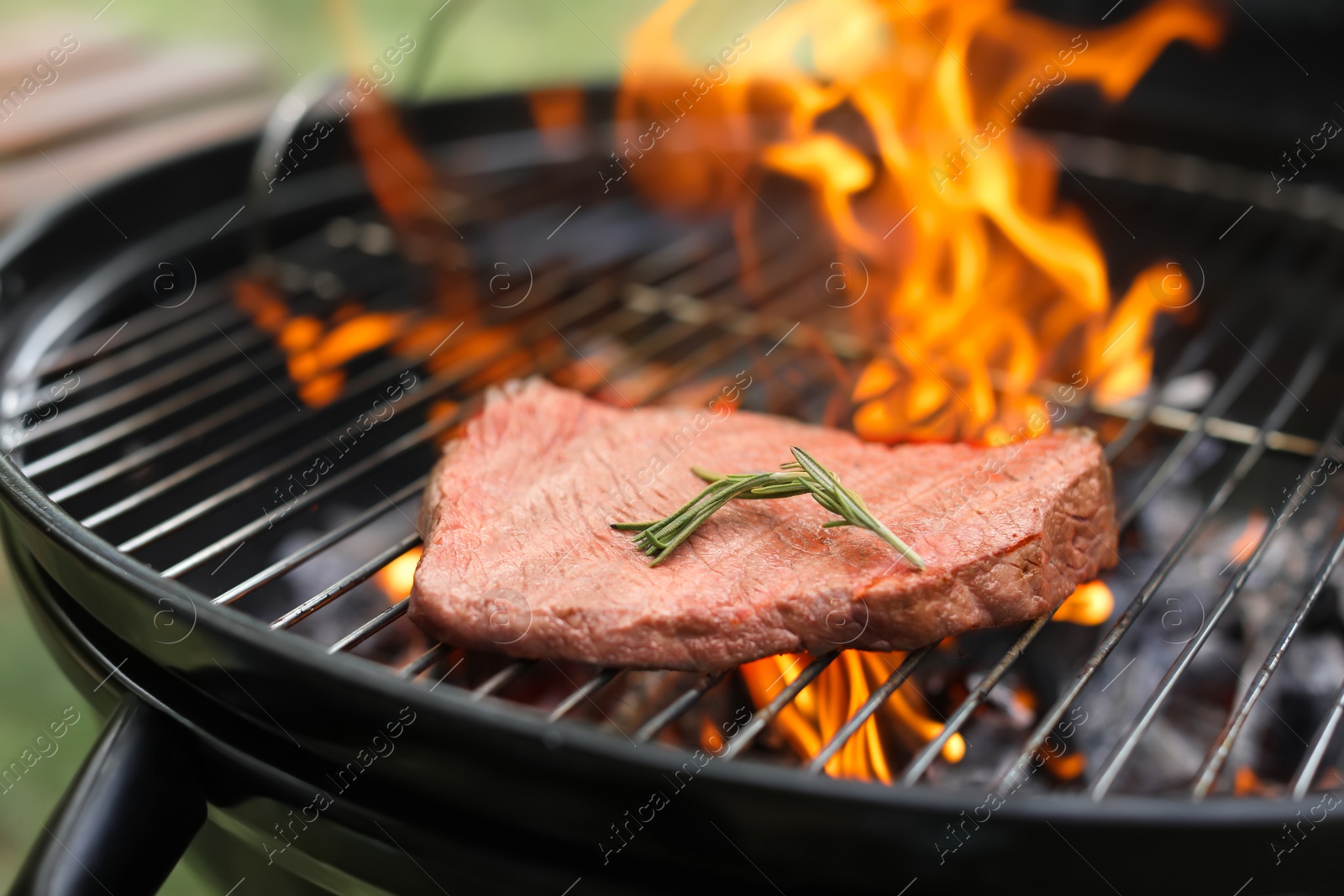 Photo of Tasty meat on barbecue grill with fire flames outdoors, closeup