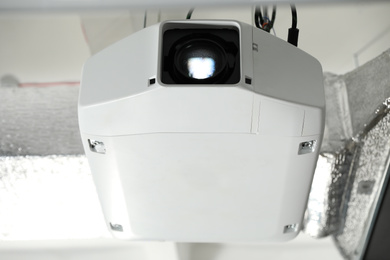 Photo of Modern video projector hanging on ceiling, closeup