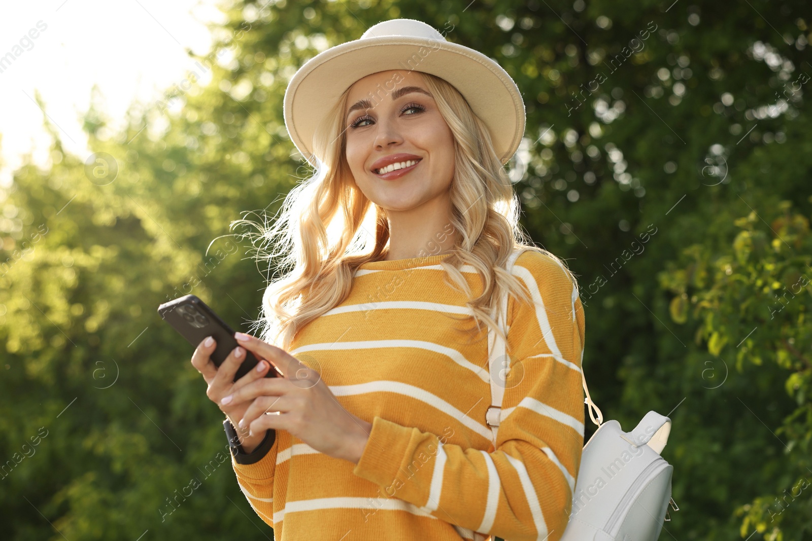 Photo of Happy young woman using smartphone in park on spring day