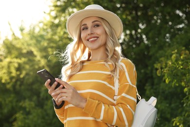 Photo of Happy young woman using smartphone in park on spring day