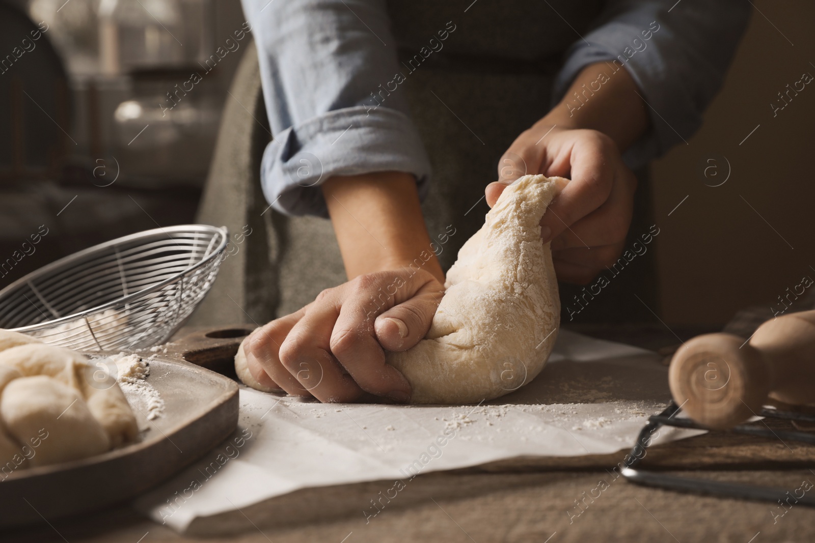 Photo of Woman making braided bread at wooden table indoors, closeup. Traditional Shabbat challah