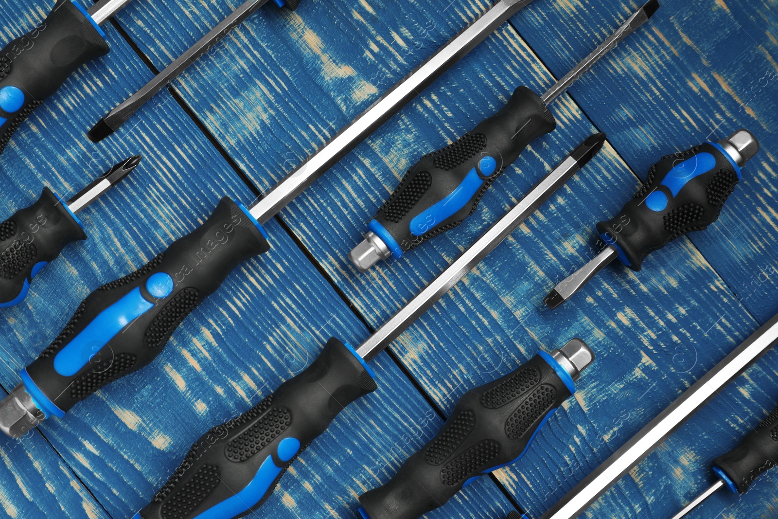 Photo of Set of screwdrivers on blue wooden table, flat lay