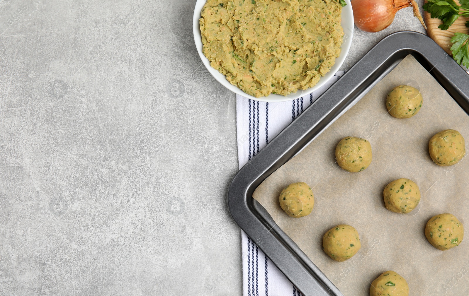 Photo of Raw falafel balls and ingredients on grey table, flat lay. Space for text