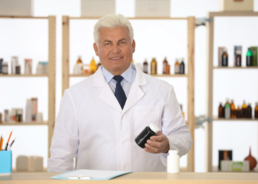 Photo of Professional pharmacist with bottle of medicine in drugstore