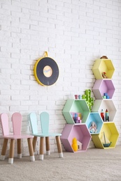 Photo of Child room interior with colorful shelves near brick wall