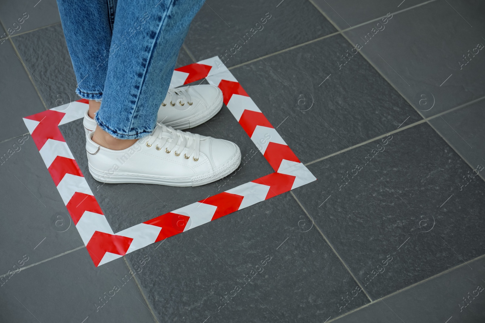 Photo of Woman standing on taped floor marking for social distance, closeup. Coronavirus pandemic