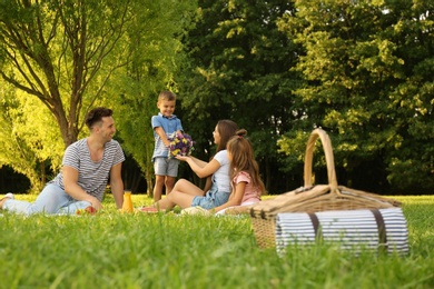 Photo of Picnic basket and happy family on background in park
