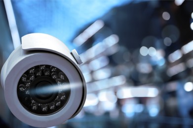 Image of Modern security CCTV camera against blurred background, space for text