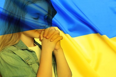 Double exposure of national flag and little girl praying. Stop war in Ukraine