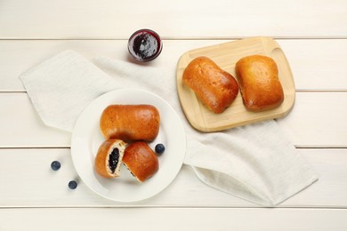 Photo of Delicious baked patties, jam and blueberries on white wooden table, flat lay