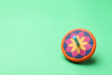 One colorful spinning top on green background, space for text