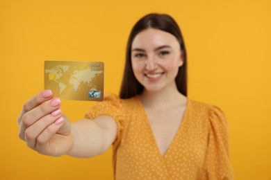 Photo of Happy woman with credit card on orange background, selective focus