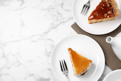 Photo of Slices of delicious cakes with caramel sauce on white marble table, flat lay. Space for text