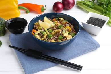 Photo of Stir-fry. Delicious cooked noodles with chicken and vegetables in bowl served on white wooden table