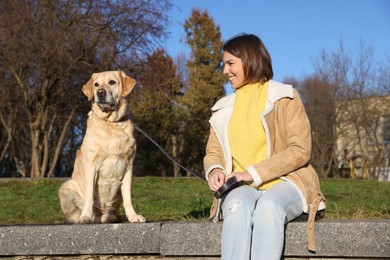 Photo of Beautiful young woman sitting with cute Labrador Retriever in park