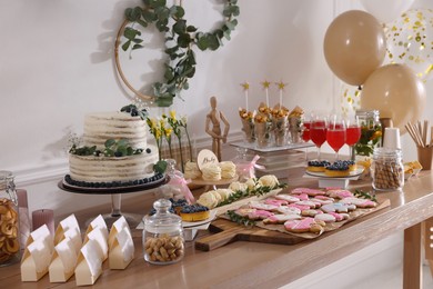 Photo of Baby shower party. Different delicious treats on wooden table indoors