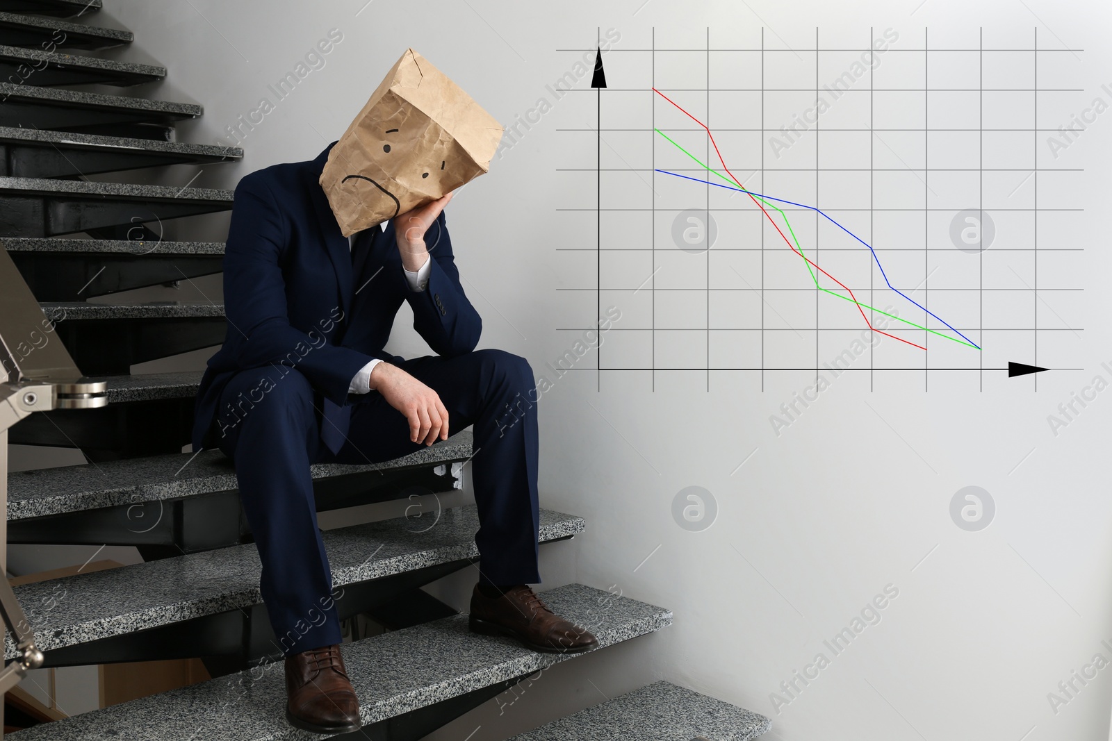 Image of Man wearing paper bag with drawn sad face indoors and illustration of falling down chart. Economy recession concept