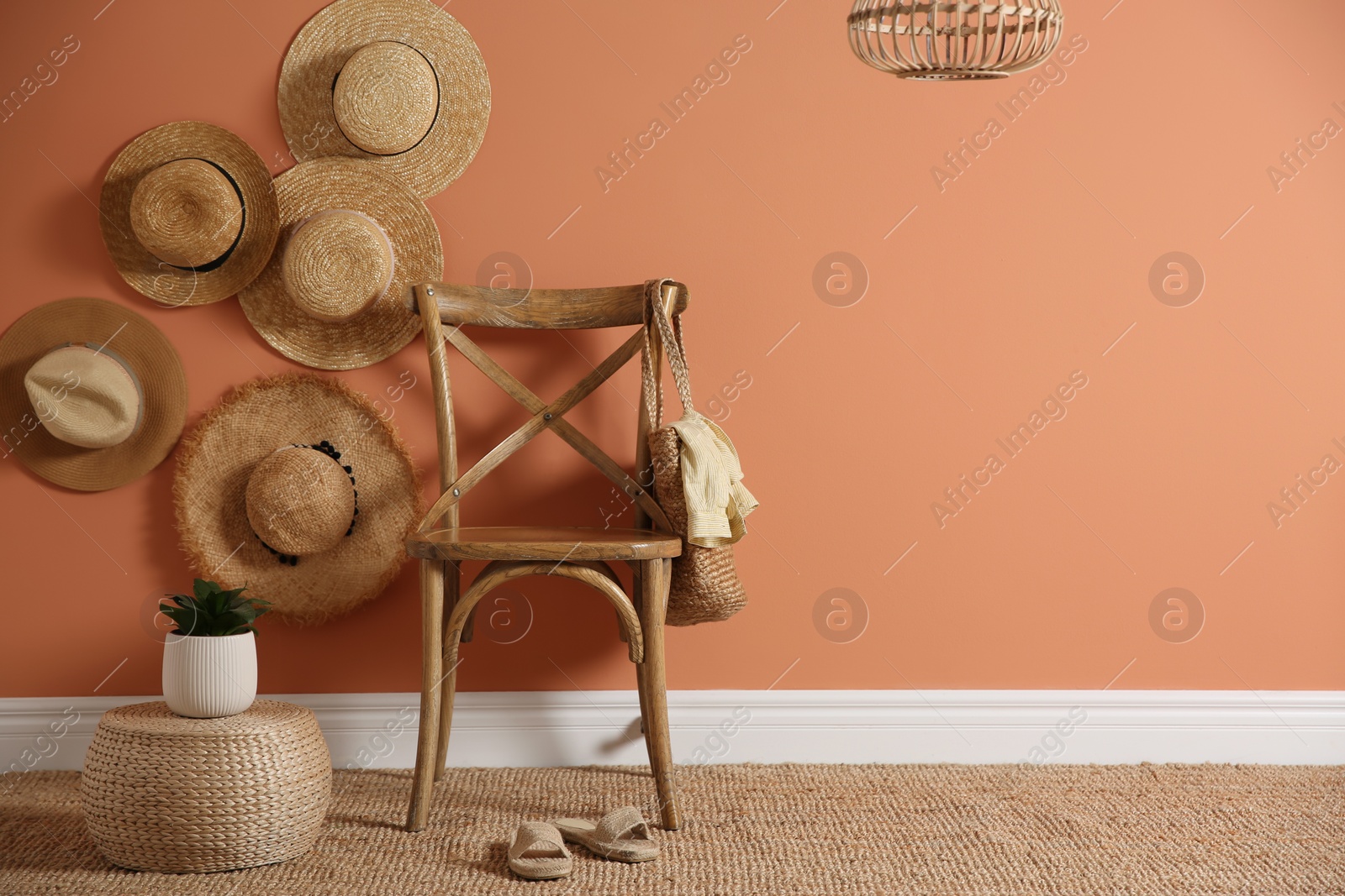 Photo of Wooden chair with bag and straw hats on brown wall, space for text. Interior design