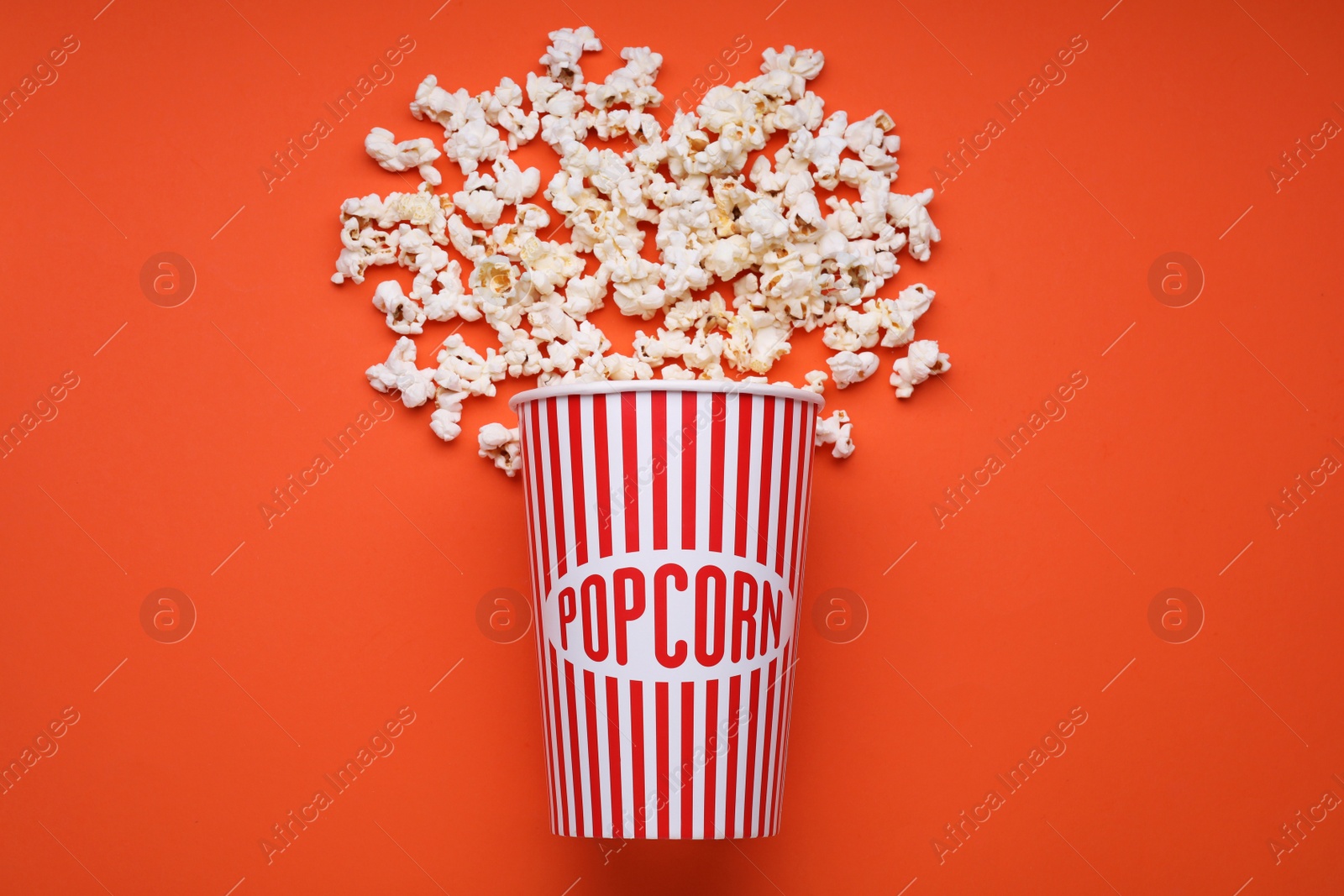 Photo of Bucket of tasty popcorn on orange background, flat lay