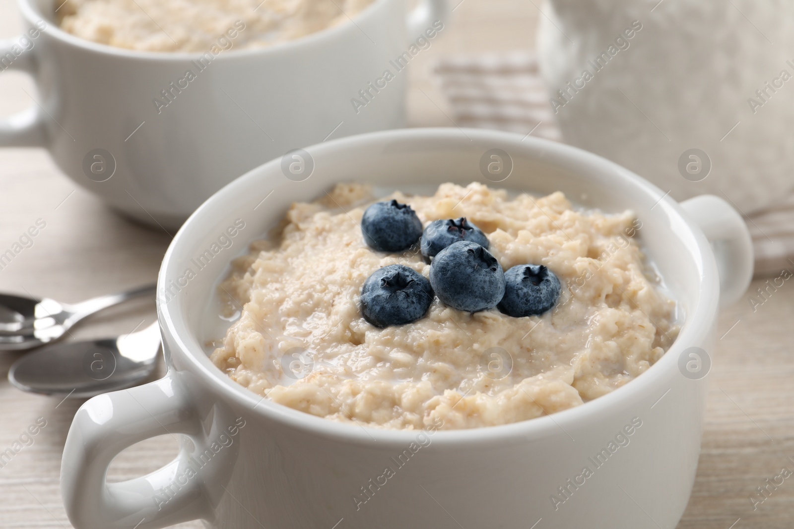 Photo of Tasty oatmeal porridge with blueberries in bowl on light table, closeup