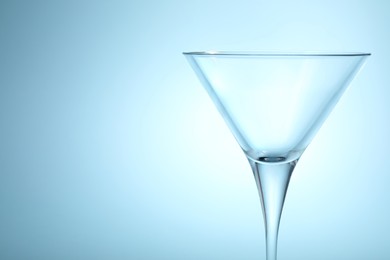 Elegant empty martini glass on light blue background, closeup. Space for text