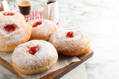 Photo of Delicious donuts with jam and powdered sugar on white marble table, closeup. Space for text