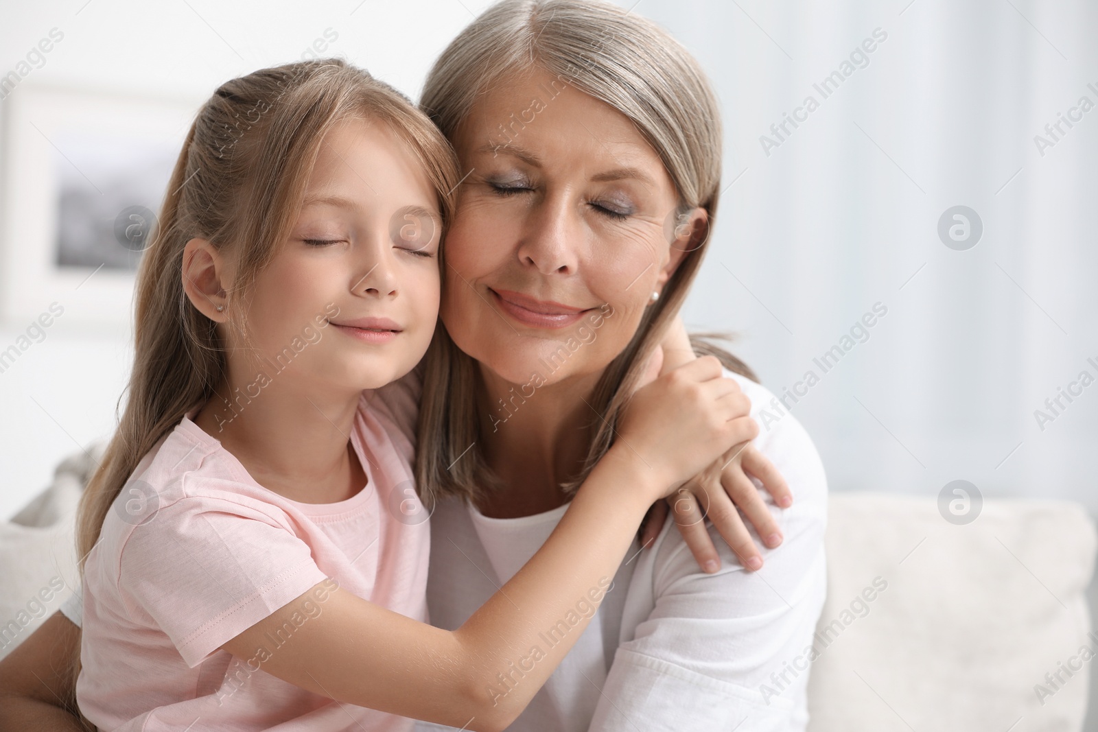 Photo of Happy grandmother hugging her granddaughter at home, space for text