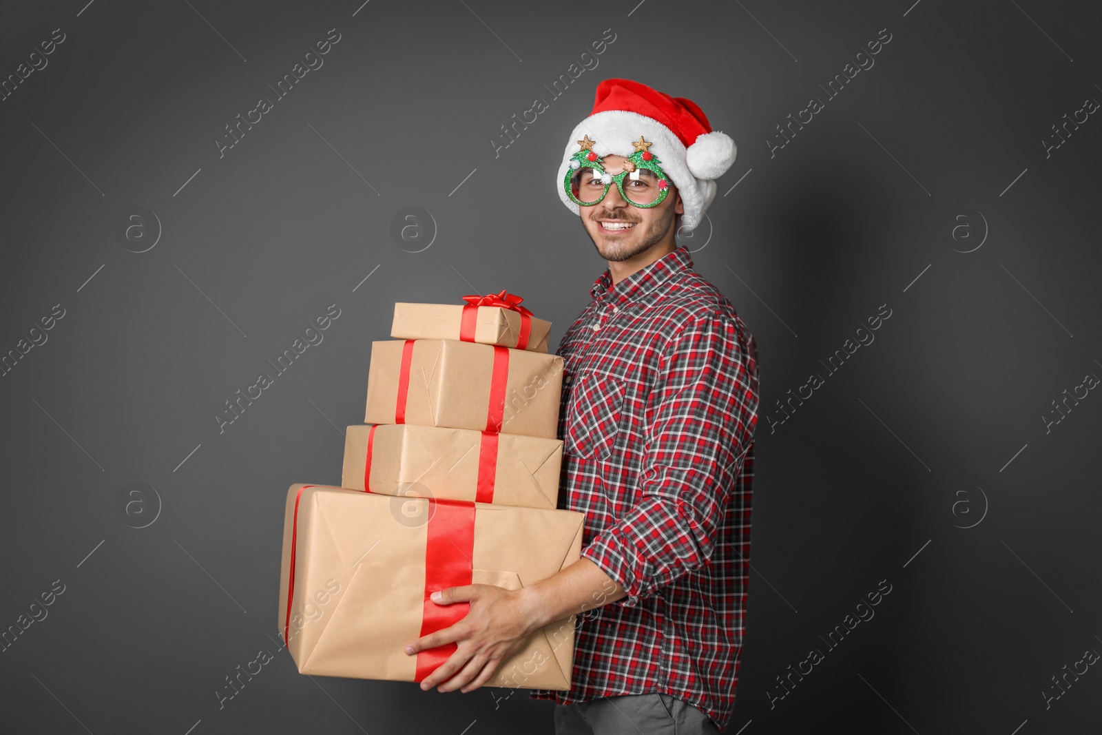 Photo of Young man with Christmas gifts on grey background