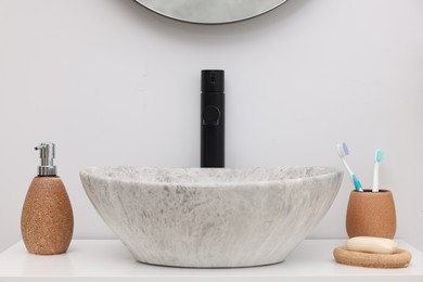 Different bath accessories and personal care products near sink on bathroom vanity