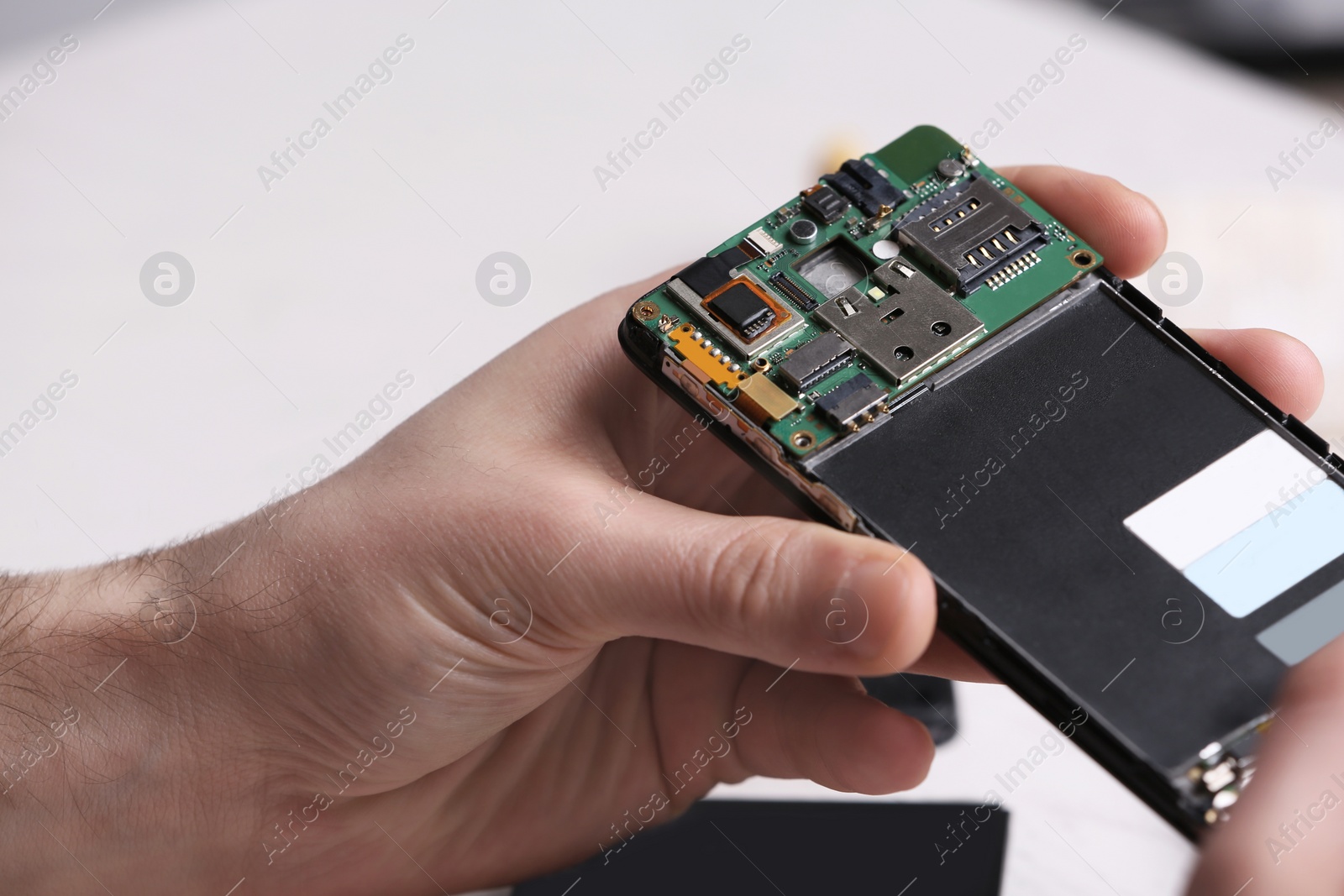 Photo of Technician fixing mobile phone at table, closeup. Device repair service