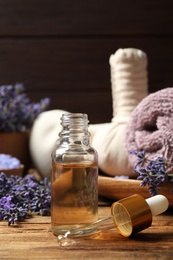 Photo of Composition with lavender flowers and essential oil on wooden table