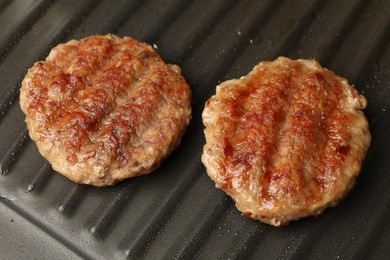 Photo of Tasty hamburger patties on grill pan, closeup