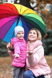 Photo of Mother and daughter with umbrella in autumn park on rainy day