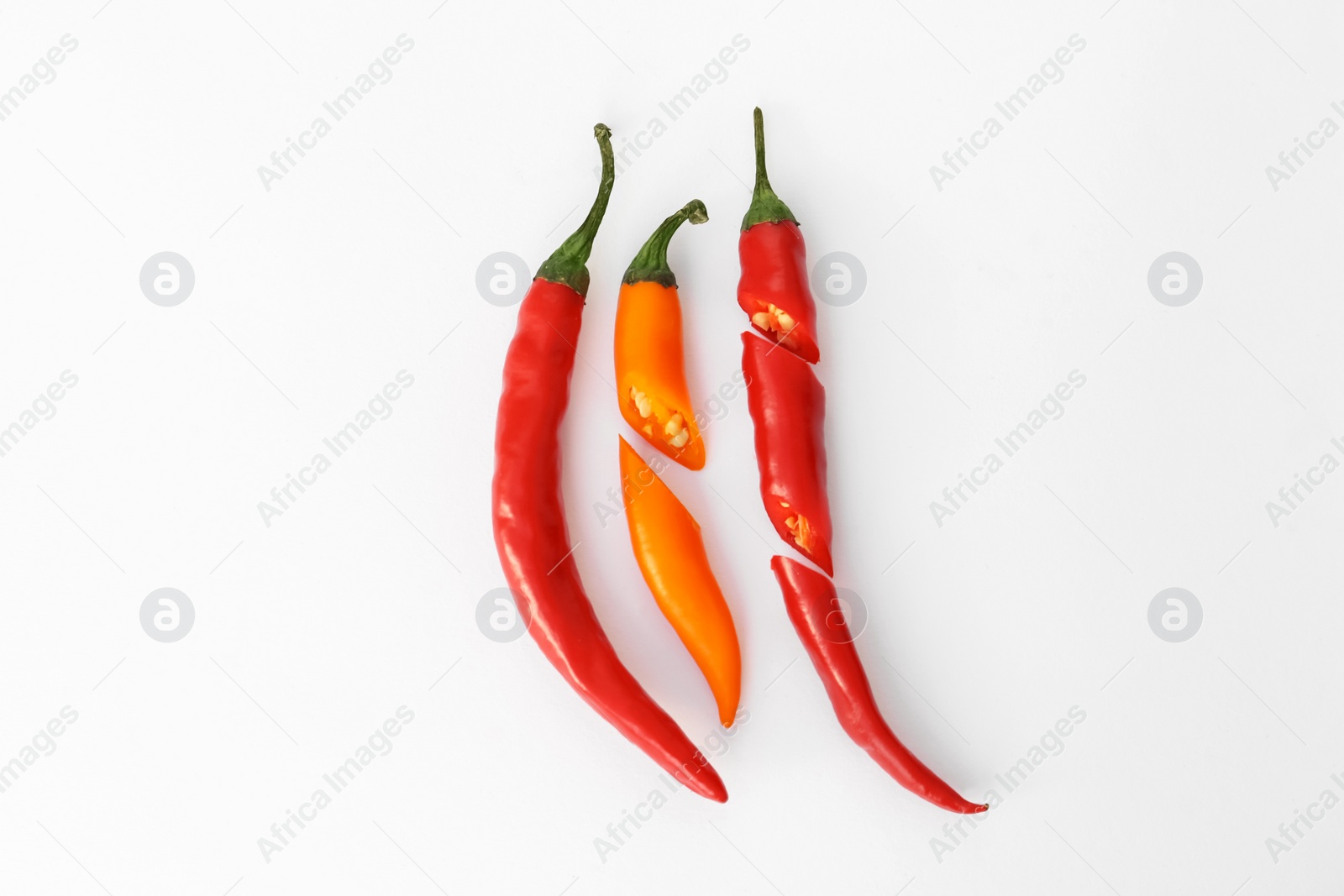 Photo of Whole and cut different hot chili peppers on white background, flat lay