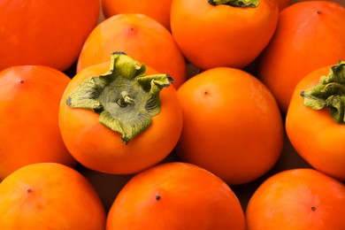 Photo of Pile of delicious ripe juicy persimmons as background, closeup