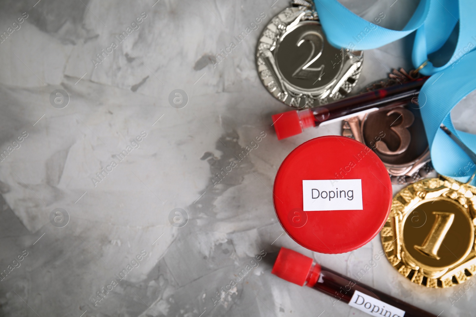 Photo of Medals, tubes of blood and urine sample with word Doping on light grey stone background, flat lay. Space for text