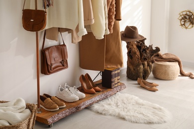 Photo of Rack with stylish shoes and women's clothes in dressing room. Modern interior design