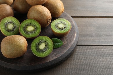 Photo of Fresh ripe kiwis on wooden table, space for text