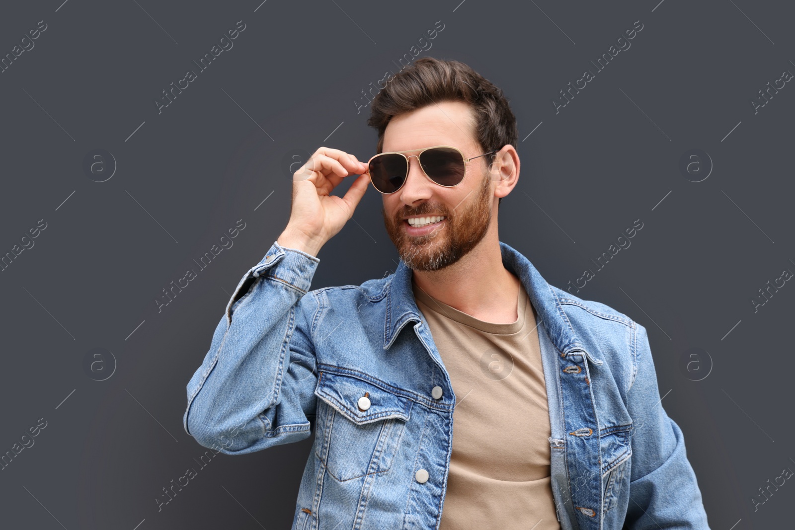 Photo of Portrait of handsome bearded man with sunglasses on grey background. Space for text