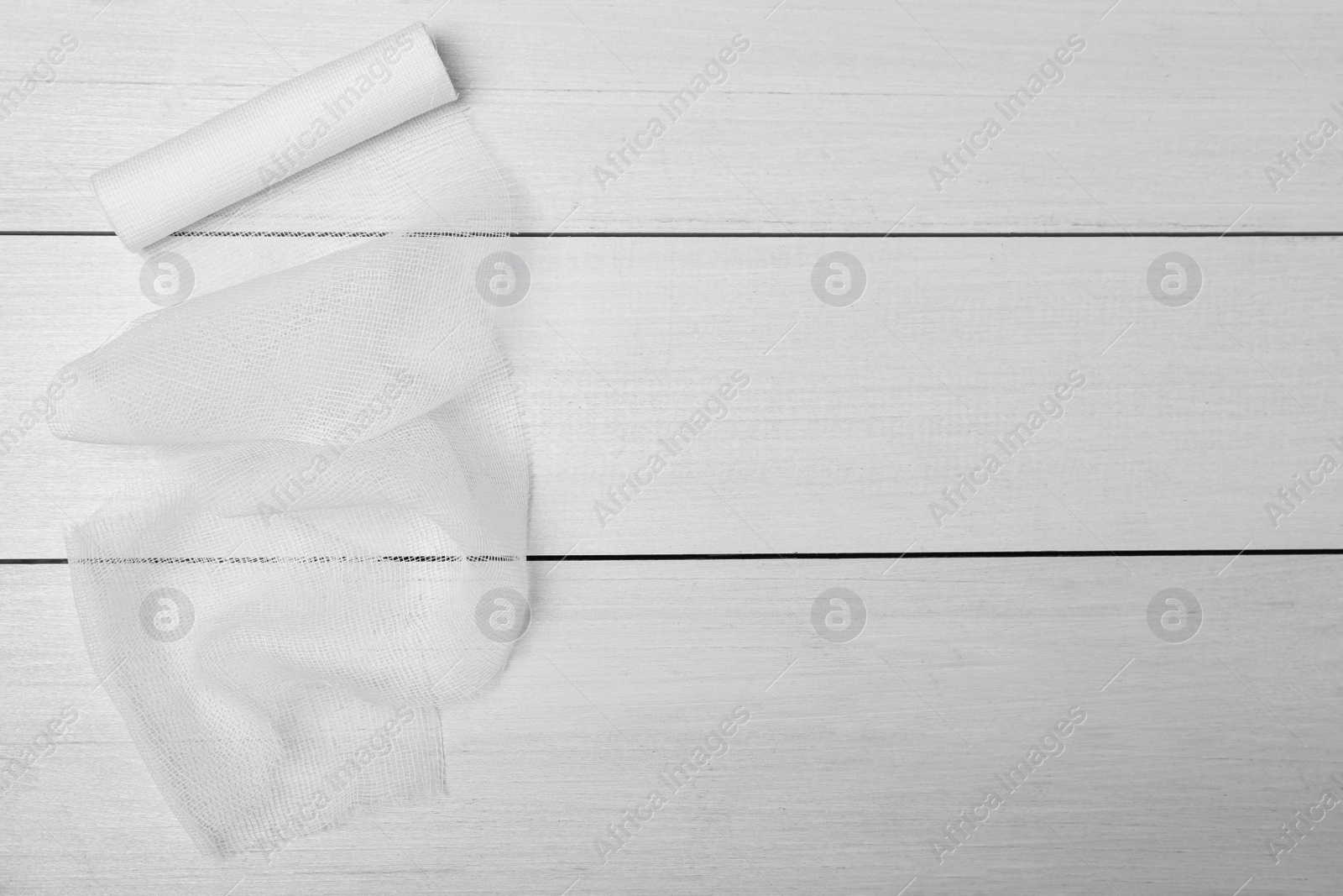 Photo of Medical bandage on white wooden table, top view. Space for text