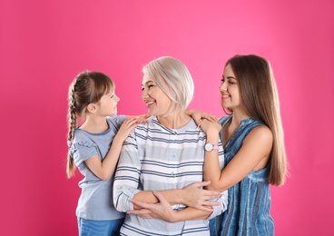 Beautiful mature woman with daughter and grandchild on color background