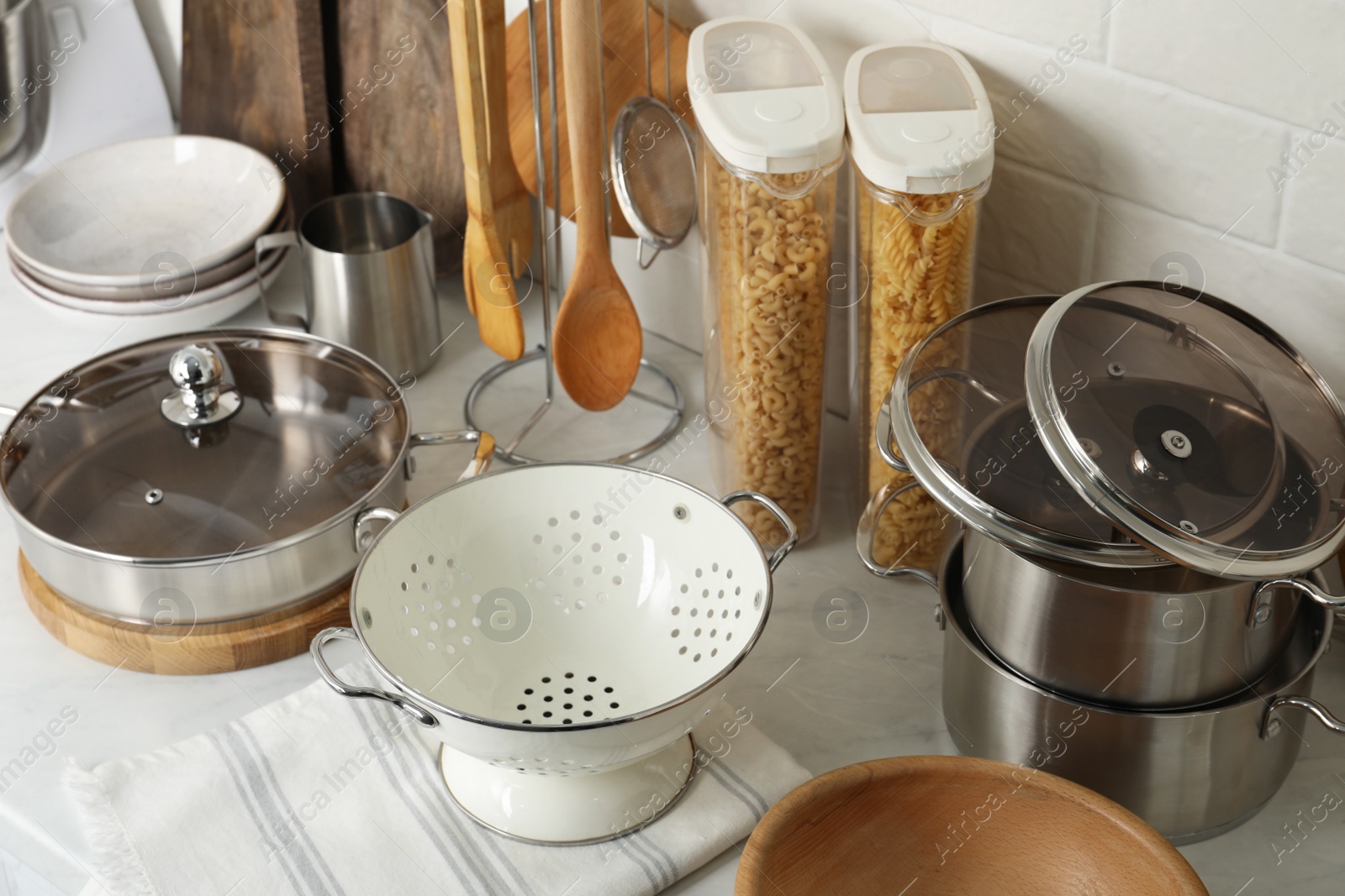 Photo of Different cooking utensils and raw pasta on countertop in kitchen, above view