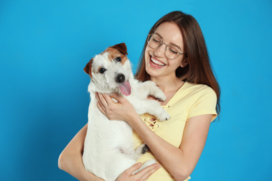 Photo of Young woman with her cute Jack Russell Terrier on light blue background. Lovely pet