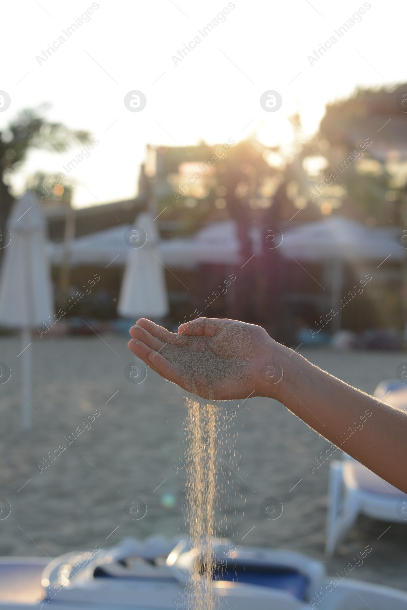 Photo of Girl pouring sand from hand on beach, closeup. Fleeting time concept