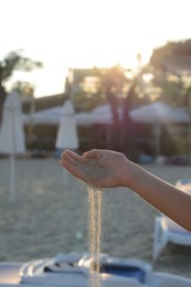 Photo of Girl pouring sand from hand on beach, closeup. Fleeting time concept