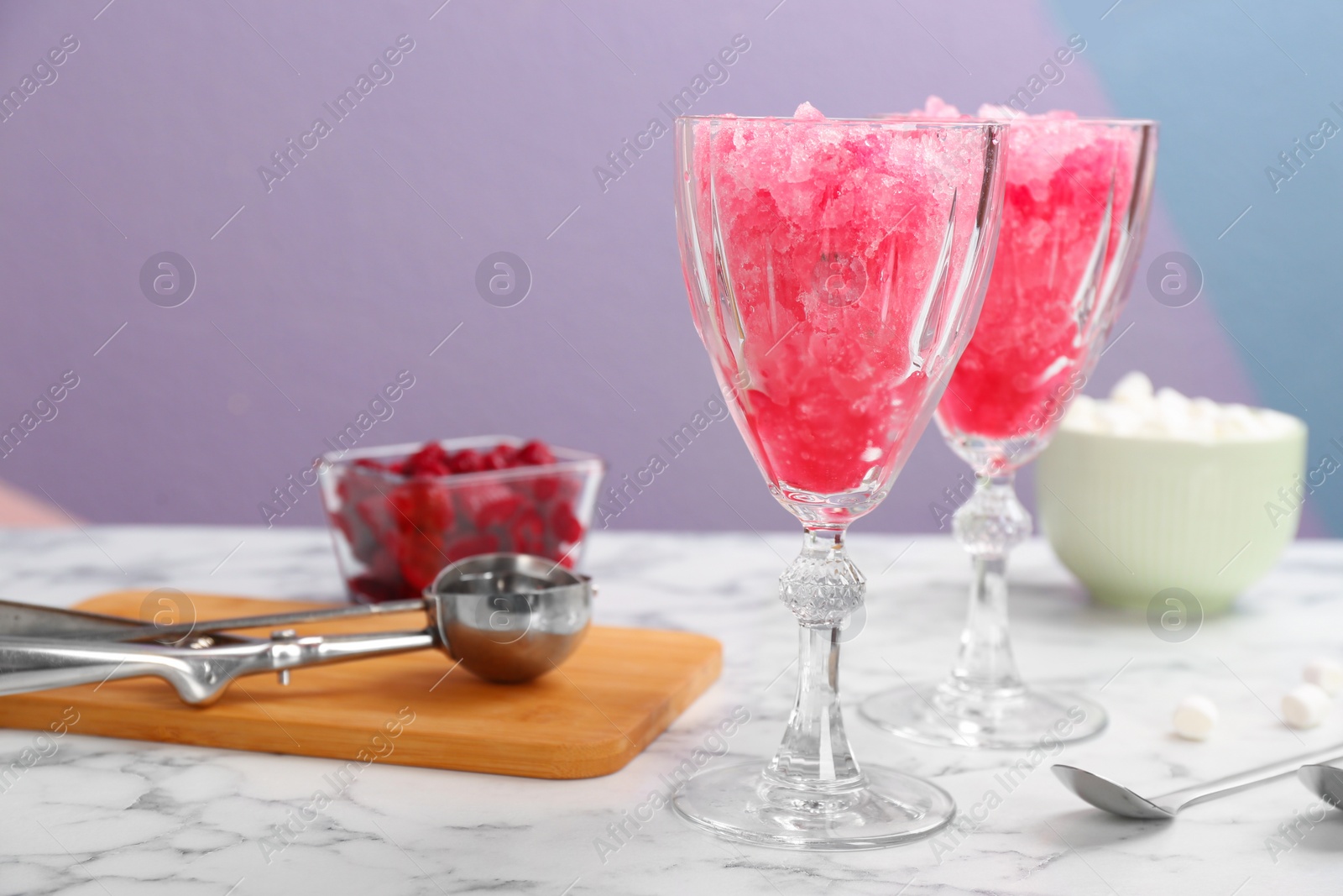 Photo of Glasses of tasty raspberry snow ice cream on table against color background. Space for text