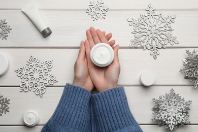 Photo of Woman with jar of hand cream at white wooden table, top view